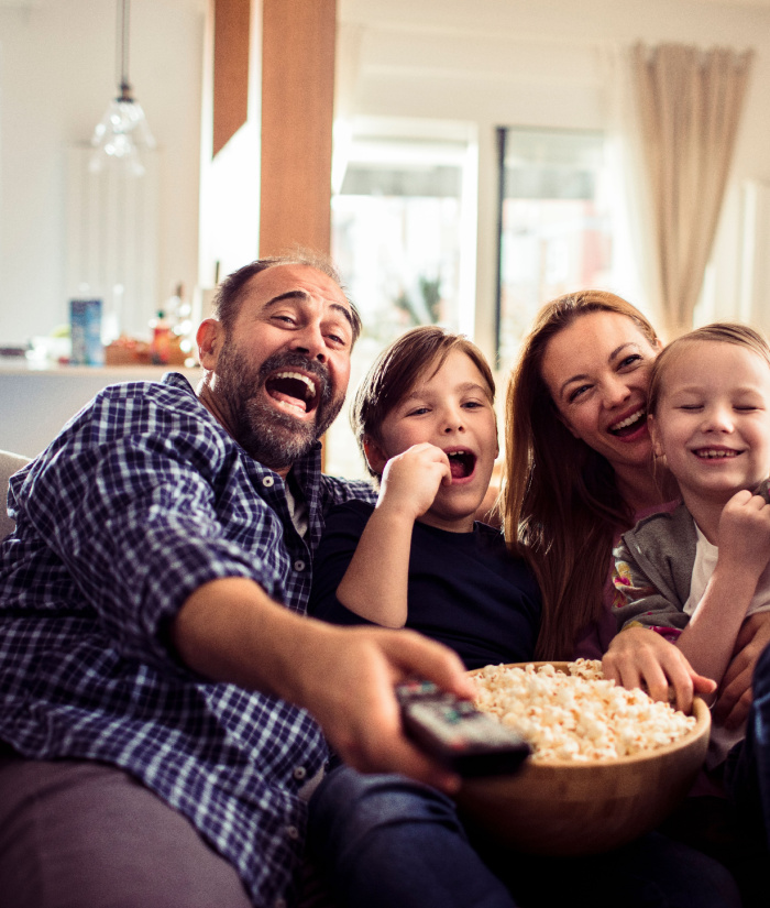 Happy family watching streaming TV together on the couch with popcorn